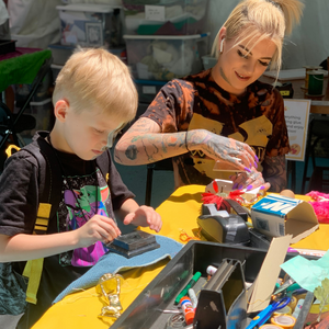 An adult and child work on art projects at a table