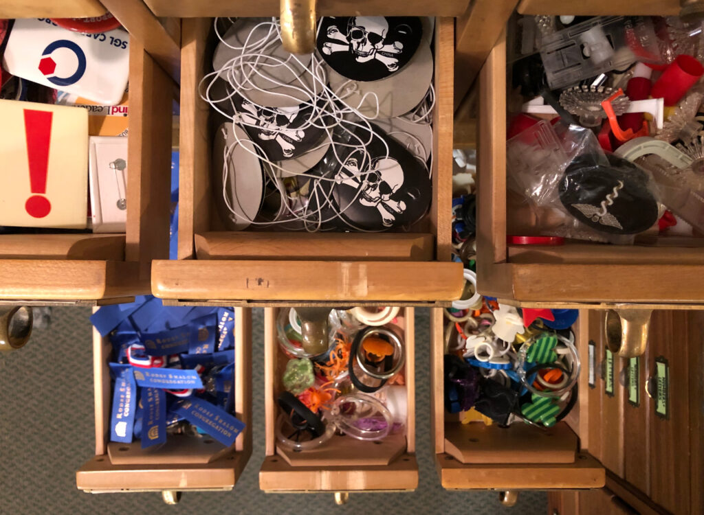 Looking down on pulled out drawers of a card catalog that are filled with small bits and bobs.