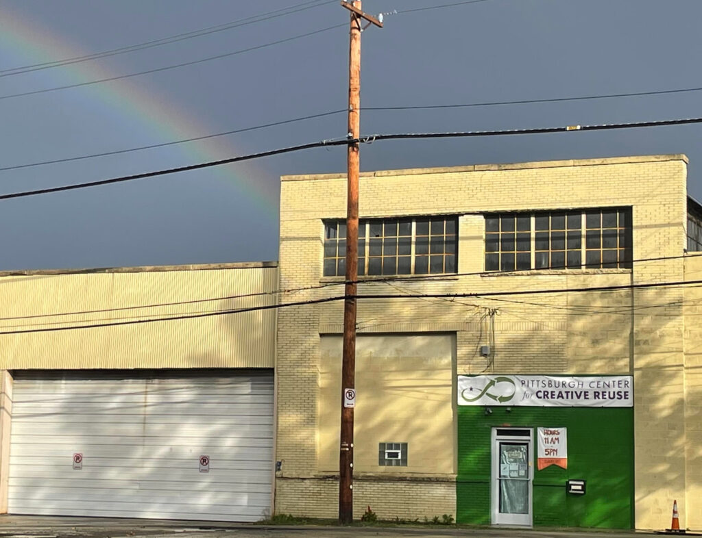 Facade and front door of Creative Reuse with a real rainbow in the sky above.