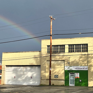 Facade and front door of Creative Reuse with a real rainbow in the sky above. Photo by Miranda Kuchera