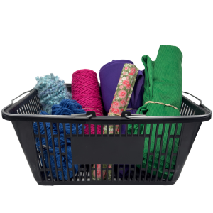 A black plastic shopping basket filled with colorful yarns and fabrics.